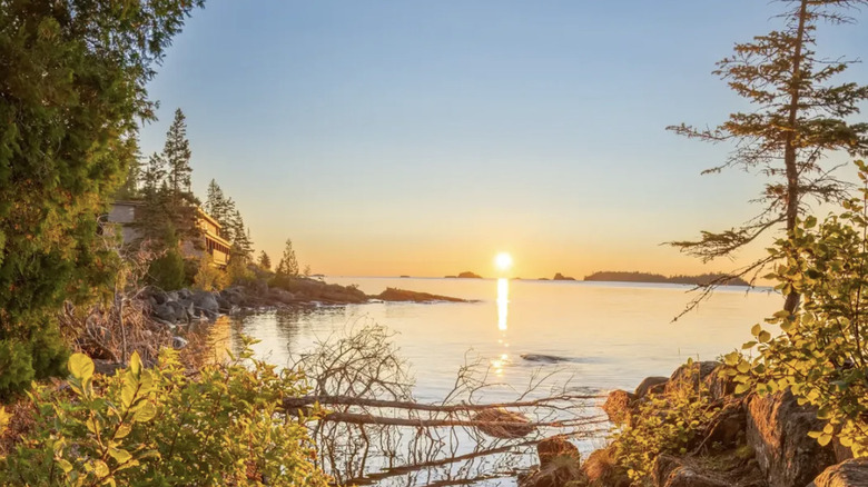 Yellow trees frame a cove on the shores of Isle Royale National Park overlooking a sunset on Lake Superior