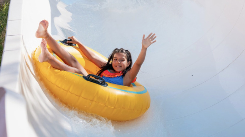 A young girl riding an inner tube slide at a water park.
