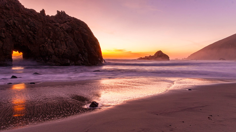 A dramatic sunlight baths the sand in shades of purple at Pfeiffer Beach, Big Sur, California