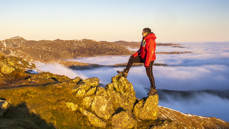 person on rocky mountain ridge in morning mist