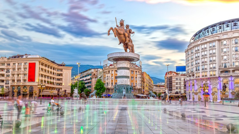 bronze statue of man on horseback in square with fountains