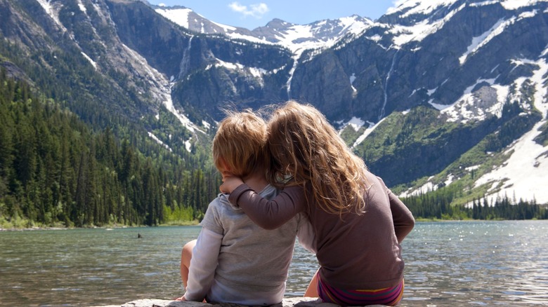 Two children sitting on a rock overlooking Glacier National Park's Avalanche Lake