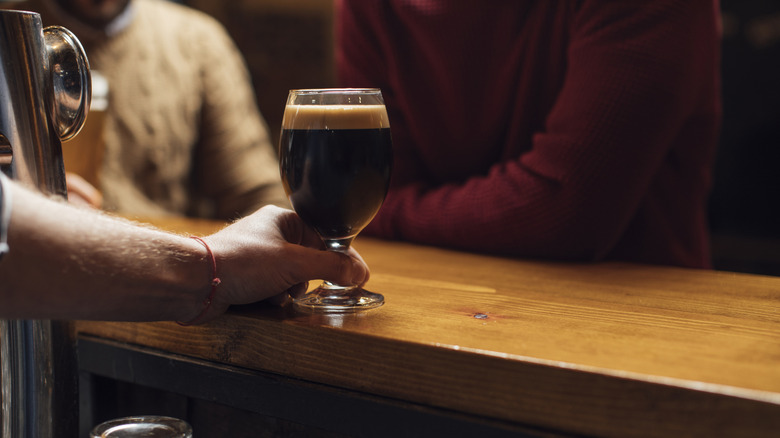 Bartender serving a glass of stout