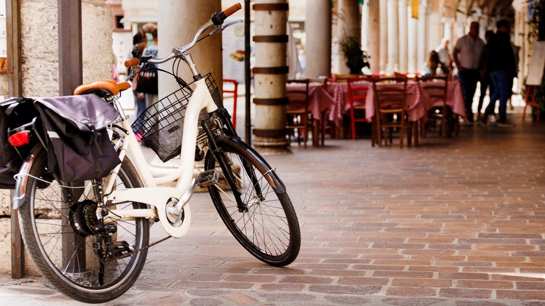 A white bicycle resting on the wall outside a restaurant patio