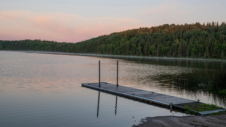 Boat launch out onto lake at sunset with forest background