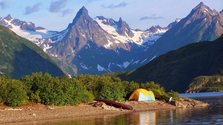 tent near a lake with rugged snow-covered peaks in the background in Wood-Tickchik State Park