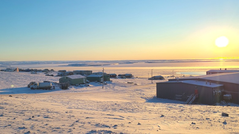 snowy community of Sachs Harbour on Banks Island with sun rising in the distnace