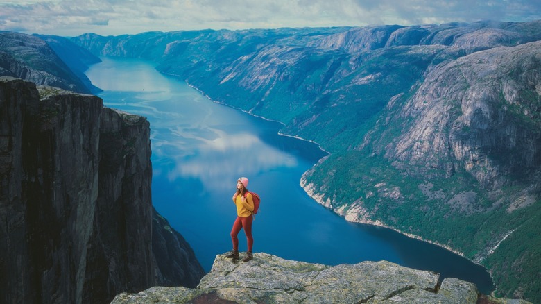 Woman hiking on a cliff with fjord landscape