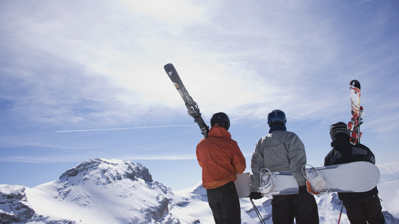 Friends holding skis and snowboards