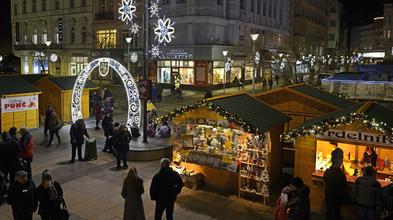 A busy Christmas market with large wooden stalls and decorative lights