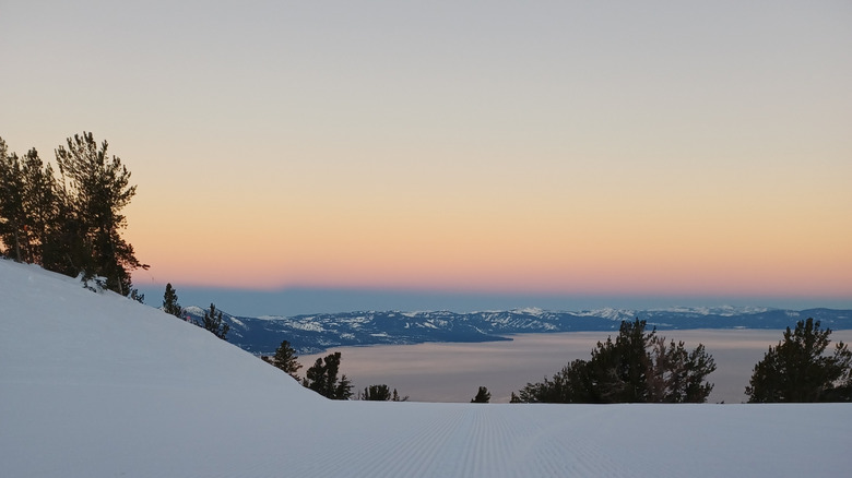 Sunrise at Heavenly ski resort with Lake Tahoe in the distance on a groomed run.