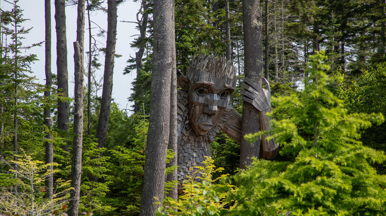 Troll sculpture between tree trunks at Coastal Maine Botanical Gardens in Boothbay, Maine