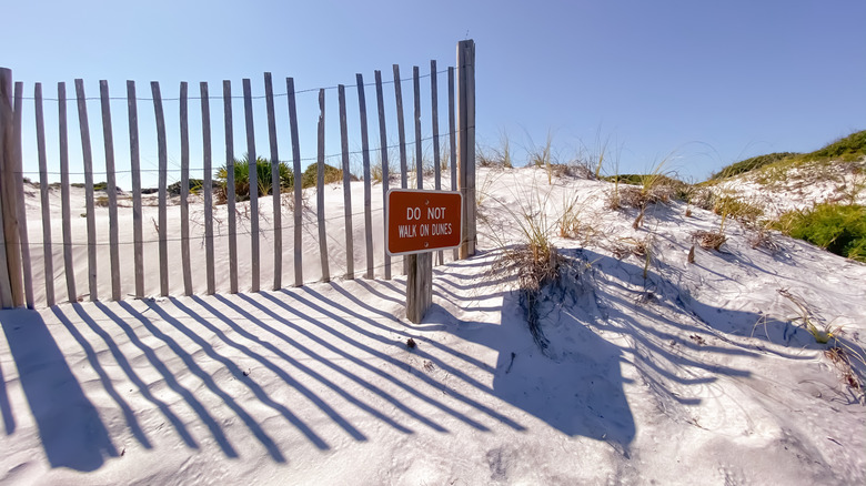 White sand dunes with sign to sat off dunes at Grayton Beach State Park in Florida