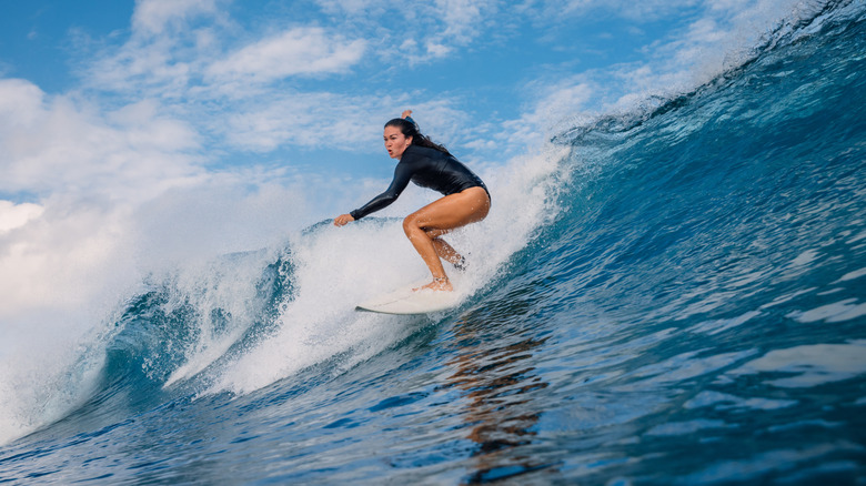 Female surfer on surfboard during surfing. Surfer woman and ocean wave