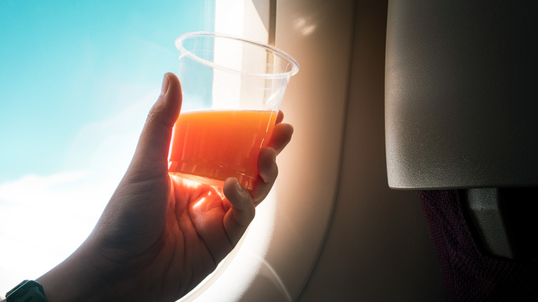 Airplane traveler holding cup of juice