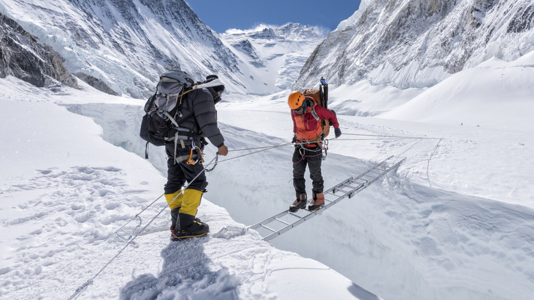 An Everest climber crosses a crevasse on a ladder