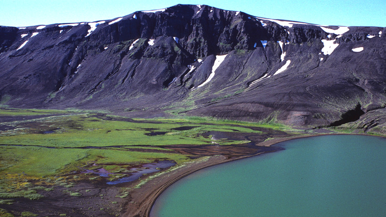 Volcanic crater with black cliffs and a green lake