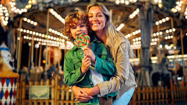 mother and son with lollypop at an amusement park