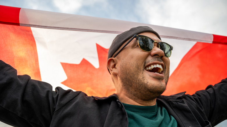 Smiling man holding up Canadian Flag