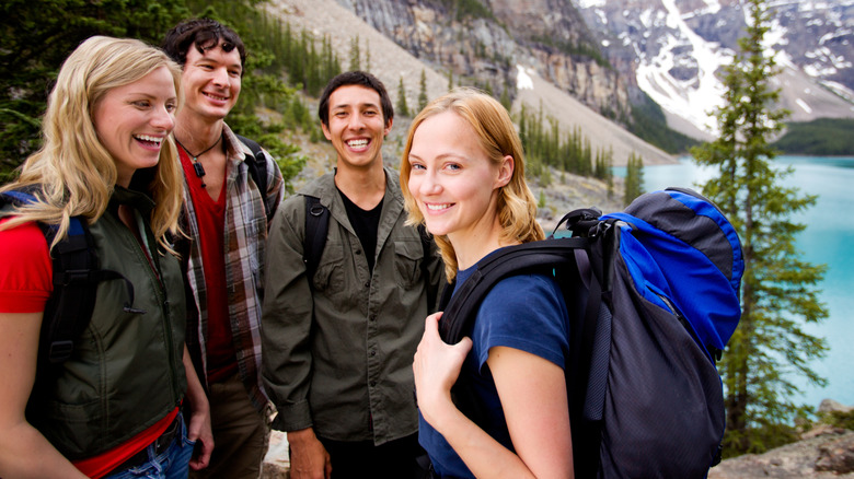 Four smiling young adults with mountains in background