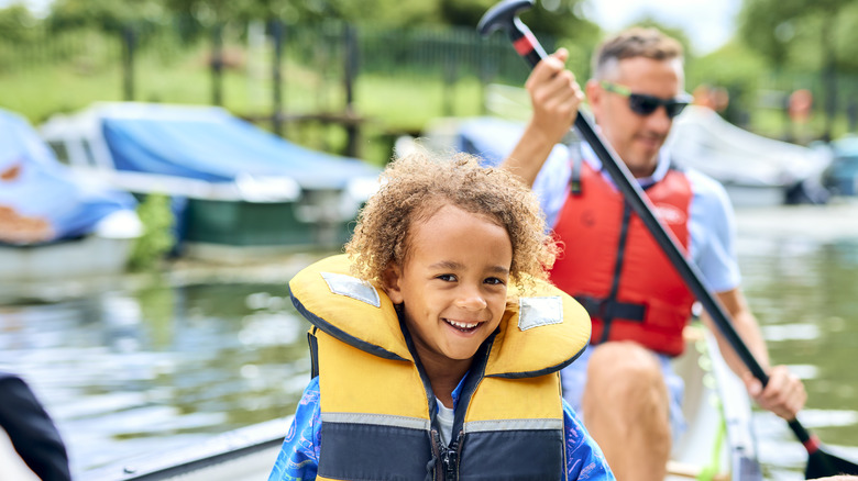 A father and child in a canoe wearing life jackets