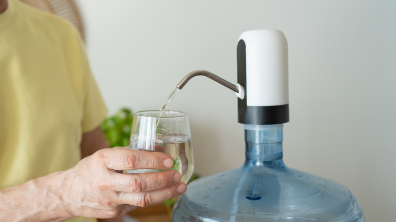 Water filtration system person pours water into cup