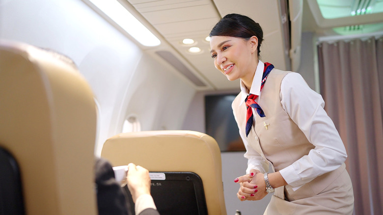 female flight attendant listening to passenger on airplane