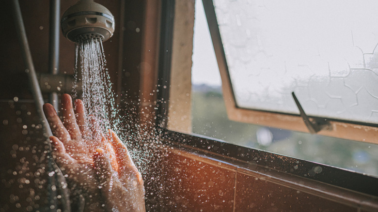 Closeup of hands under showerhead