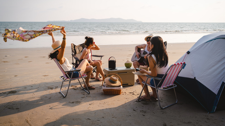 Group of Asian friends having fun enjoying beach camping in summer