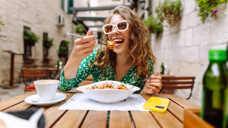 Cheerful woman eating spaghetti Bolognese
