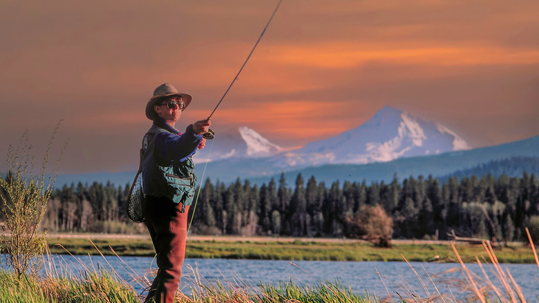 A fly-fistherman casts a line with the Three Sisters in the background, Oregon