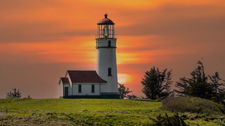 Cape Blanco Lighthouse near Port Orford, Oregon, sitting on a grassy ledge overlooking the Pacific at sunset