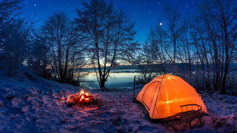 sunrise over tent in snow by lake