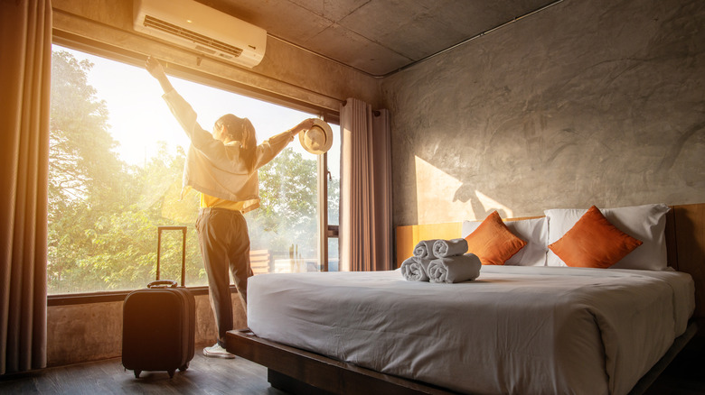 woman throwing open hotel curtains