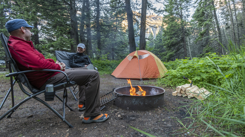 couple enjoys a campfire in a campfire ring in the wilderness