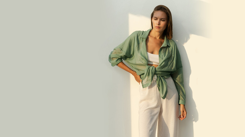 A stylish woman wearing a linen outfit while posing against a wall