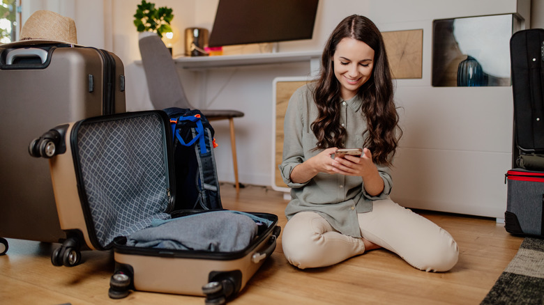 Woman sitting beside open suitcase