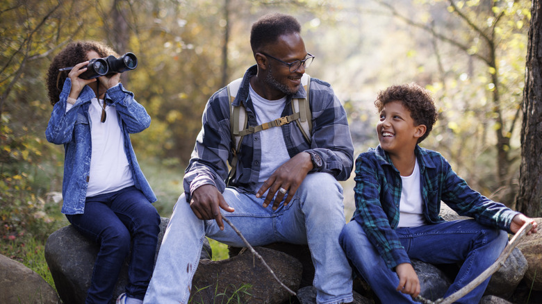 father with two kids sitting together in forest