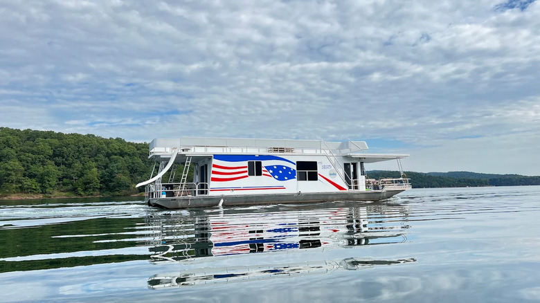 A Red, white and blue houseboat with a slide floats on the Raystown Lake