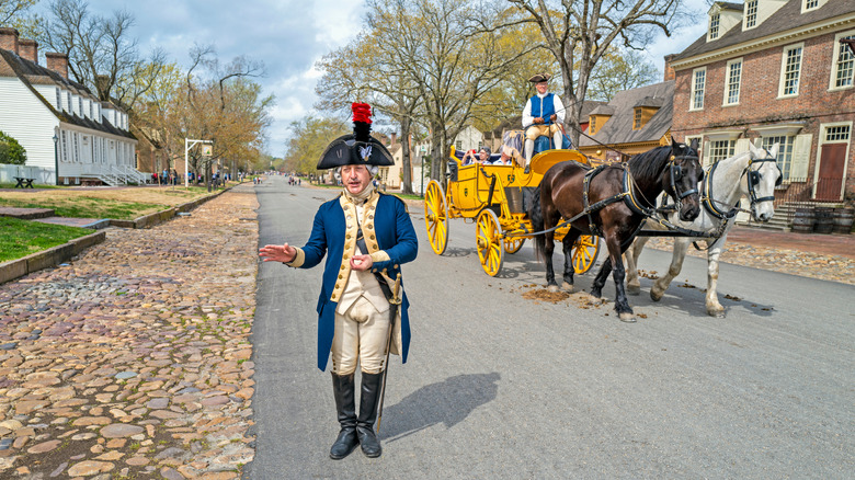 Colonial reenacter stands in street.
