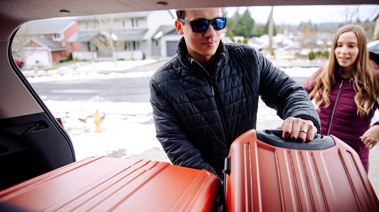 A view from inside the trunk of two people packing a car for a winter getaway.