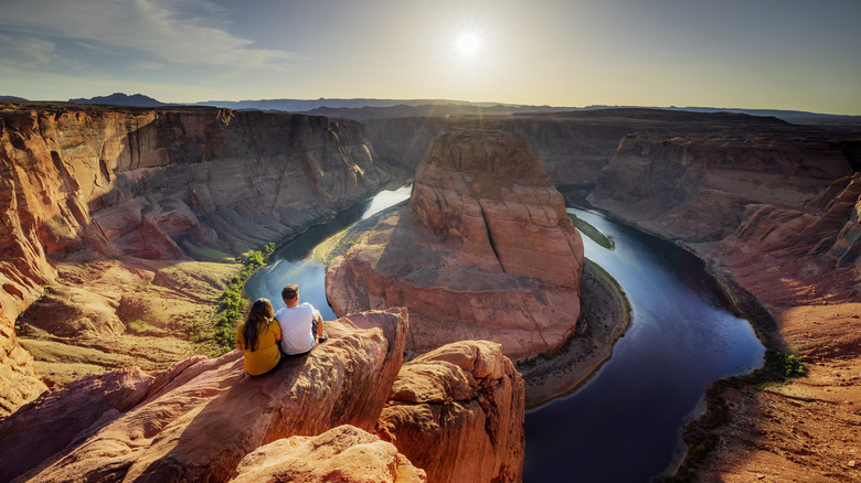 Two people sitting on rock overlooking Horseshoe Bend in Arizona