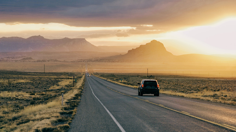 Car driving on highway through dusty plains
