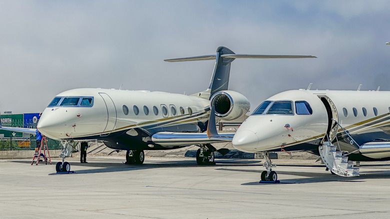 Two private jets on a runway parked side by side