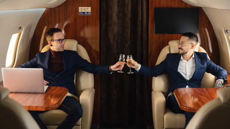 Two passengers on a private jet toasting champagne