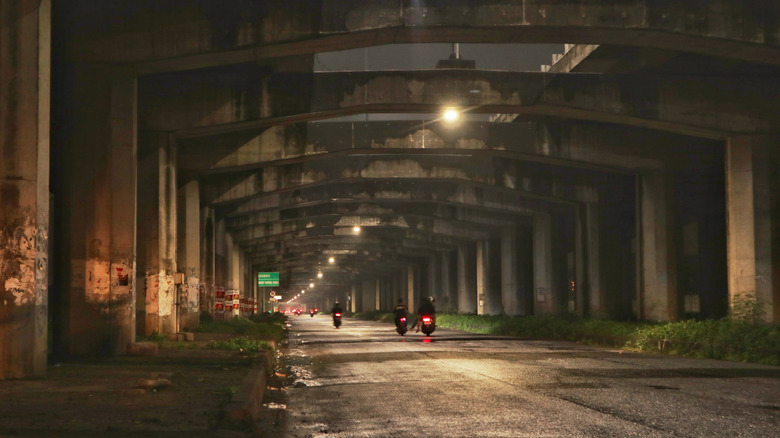 a largely empty roadway under bridge infrastructure