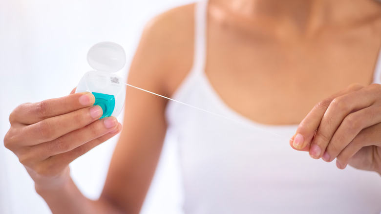 Person pulling floss from container