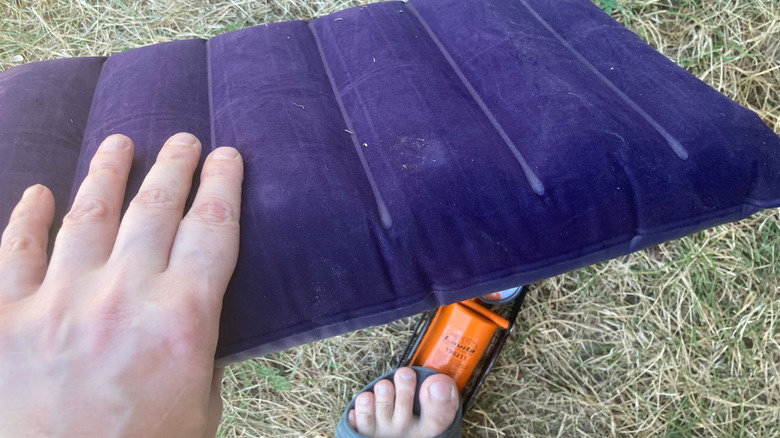 A camper inflates a pillow with a foot-pump