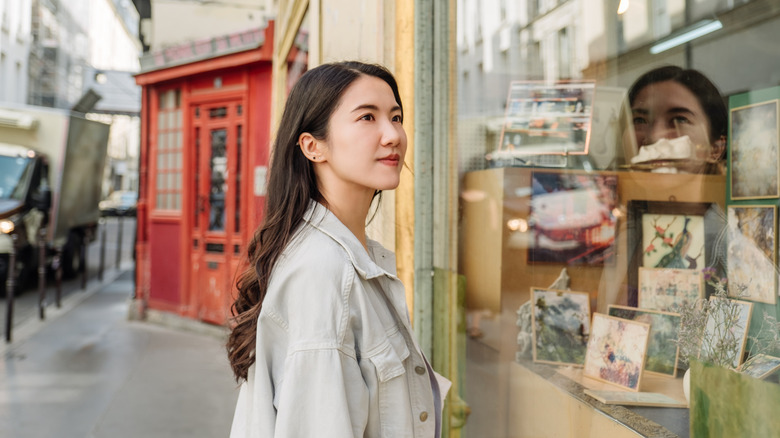 Woman looking at window display of Paris shop