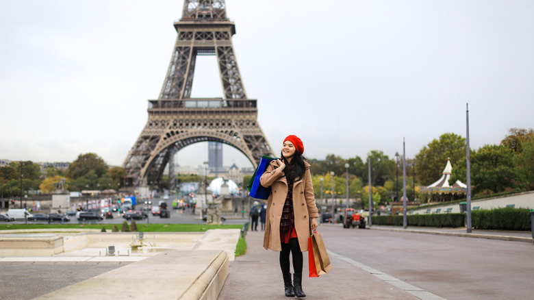 Woman holding shopping bags walking by Eiffel Tower